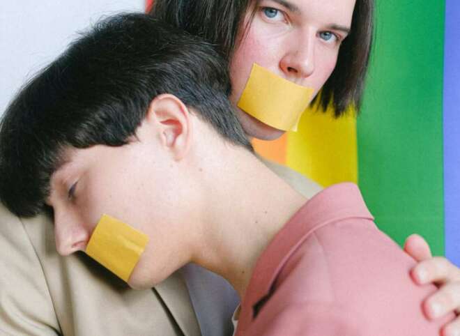 two-men-with-adhesive-tape-over-their-mouth-hugging-4611699